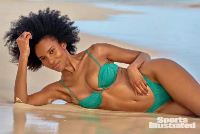 Drew Dorsey lays on the sand in a green sparkly underwire bikini.